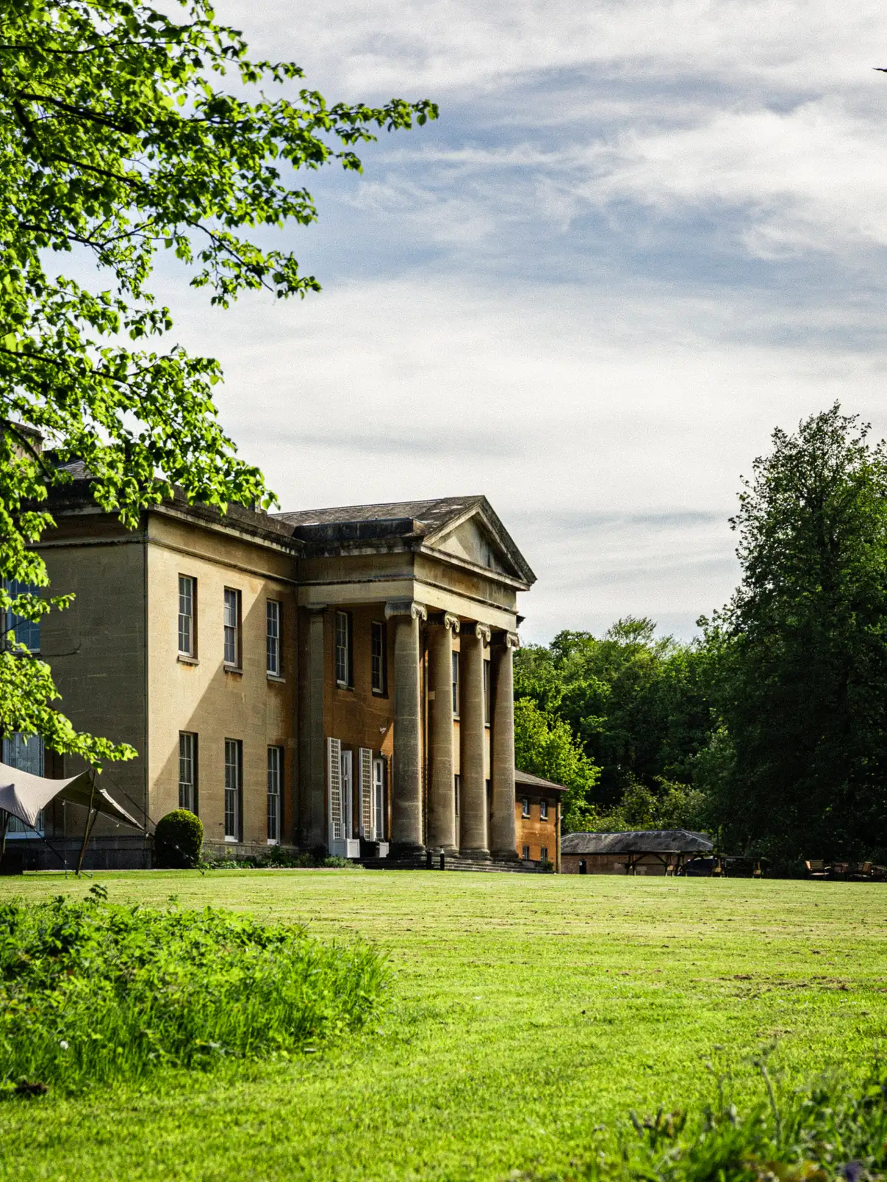 The mansion seen through tree branches.