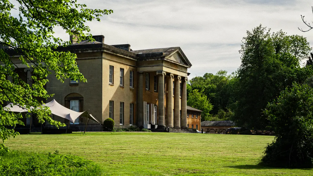 Leigh Court mansion at golden hour, mid-frame against the woodland.