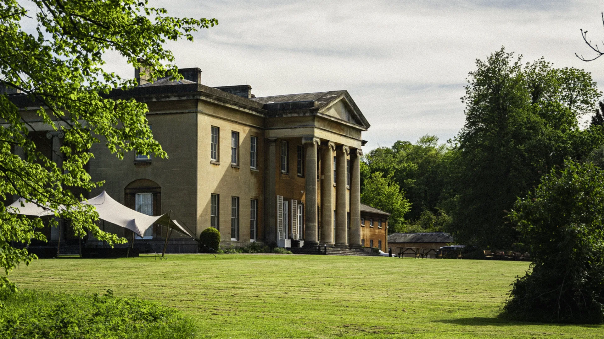 Leigh Court mansion at golden hour, mid-frame against the woodland.